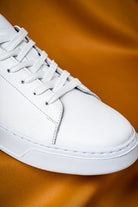 White leather low-top sneaker with matching laces and a clean, minimalist design.