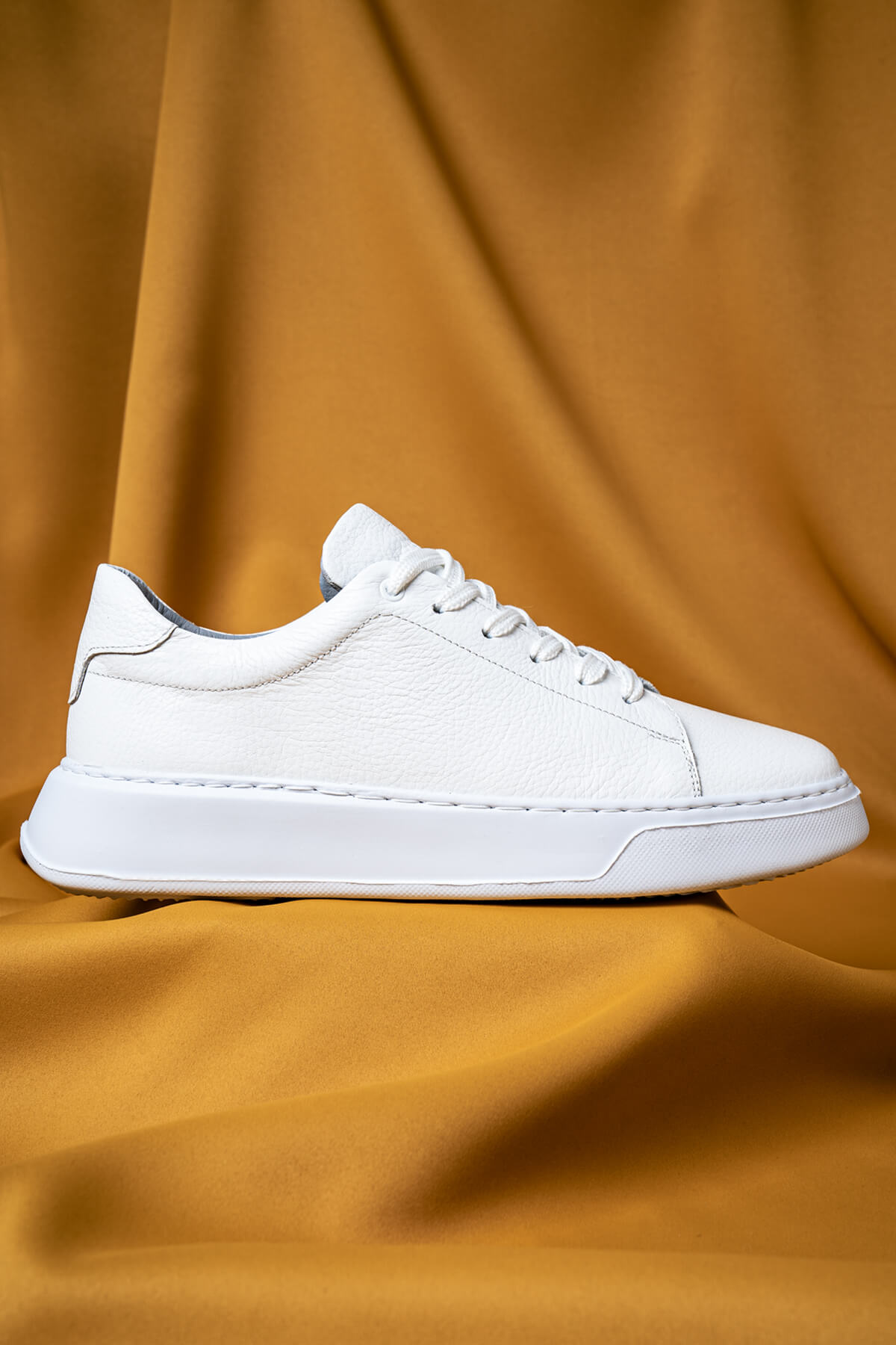 White leather low-top sneaker with clean stitching and a chunky white sole.